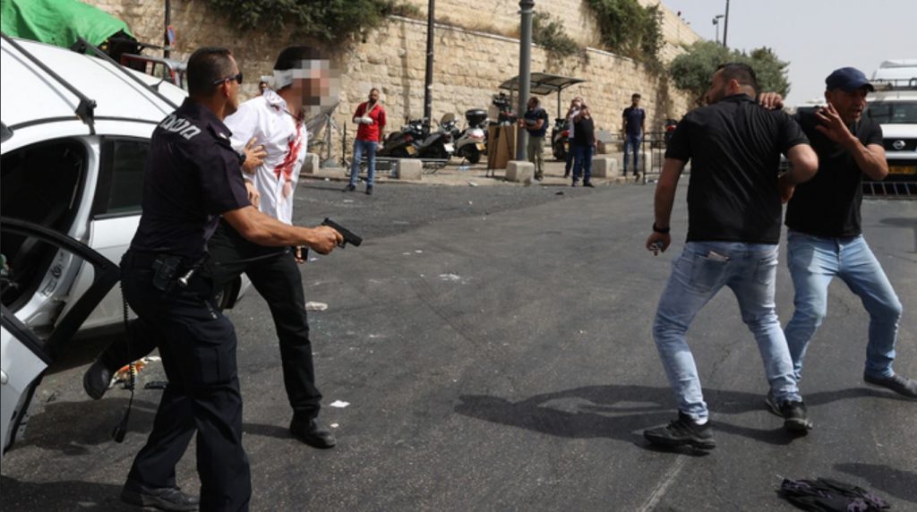 Un officier de police secourt le conducteur d'une voiture à Jérusalem après qu'il ait été attaqué par des manifestants arabes. (Photo : Amit Shabi)